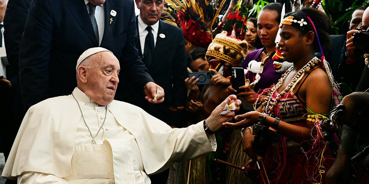 Le pape donnant des confiseries à des musiciens lors de la cérémonie d’accueil, hier à Port Moresby (Papouasie-Nouvelle-Guinée).