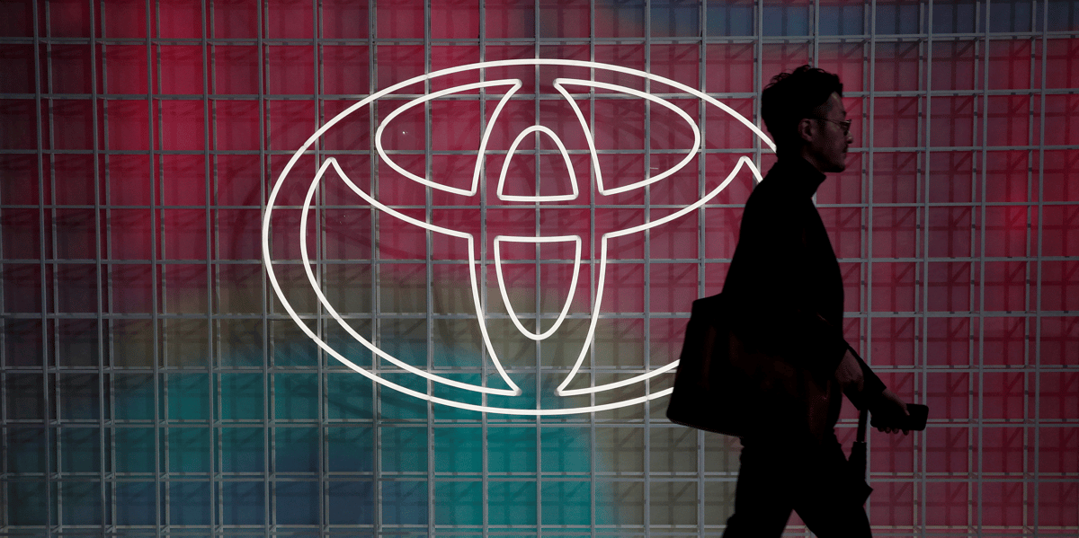 Un homme passe devant un logo toyota a tokyo
