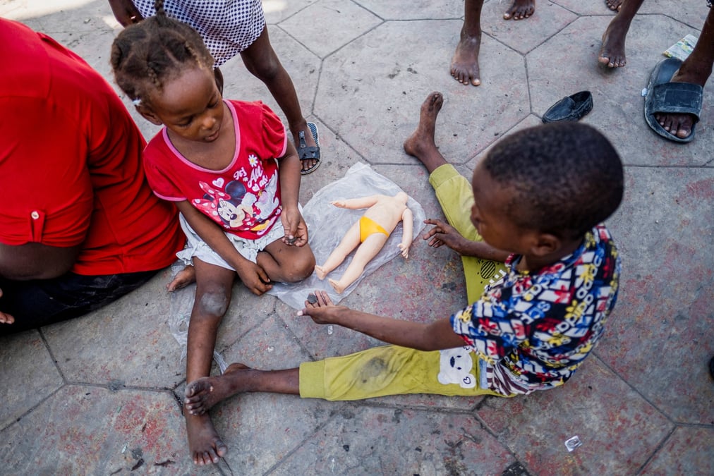 Des enfants jouent avec une poupee cassee sur la place hugo chavez a port-au-prince, haiti