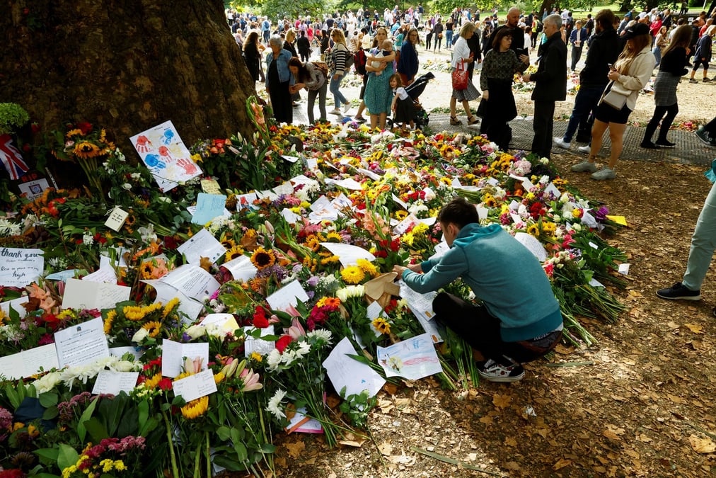 Une personne place des fleurs pres du palais de buckingham a londres suite au deces de la reine elizabeth ii