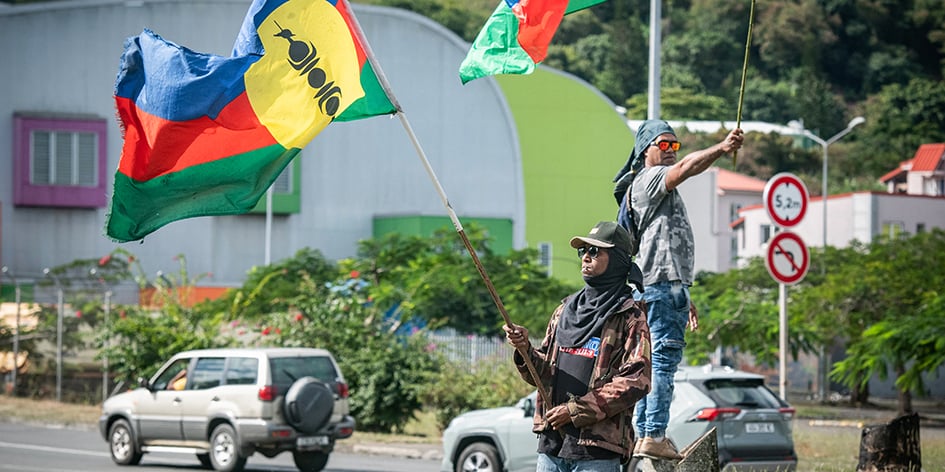 Des partisans de l’indépendance de la Nouvelle-Calédonie brandissent des drapeaux au bord d’une route à Nouméa, le 27 juin 2024.