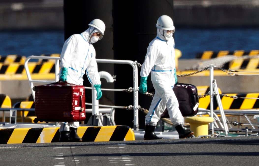 Des agents en équipements de protection sur le port de Yokohama, au sud de Tokyo (Japon), le 5 février se rendent auprès des passagers du bateau de croisière Diamond Princess où quelque dix touristes ont été déclarés contaminés par le coronavirus.