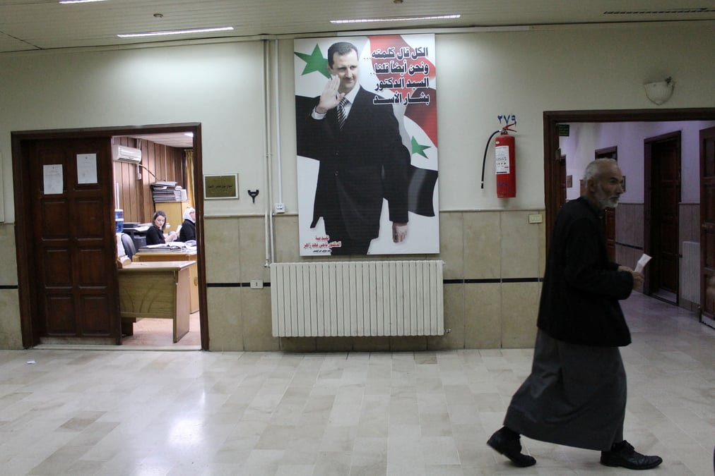 Un homme passe devant une photo du president syrien bashar al-assad a l'interieur de l'hopital ibn al-nafis a damas