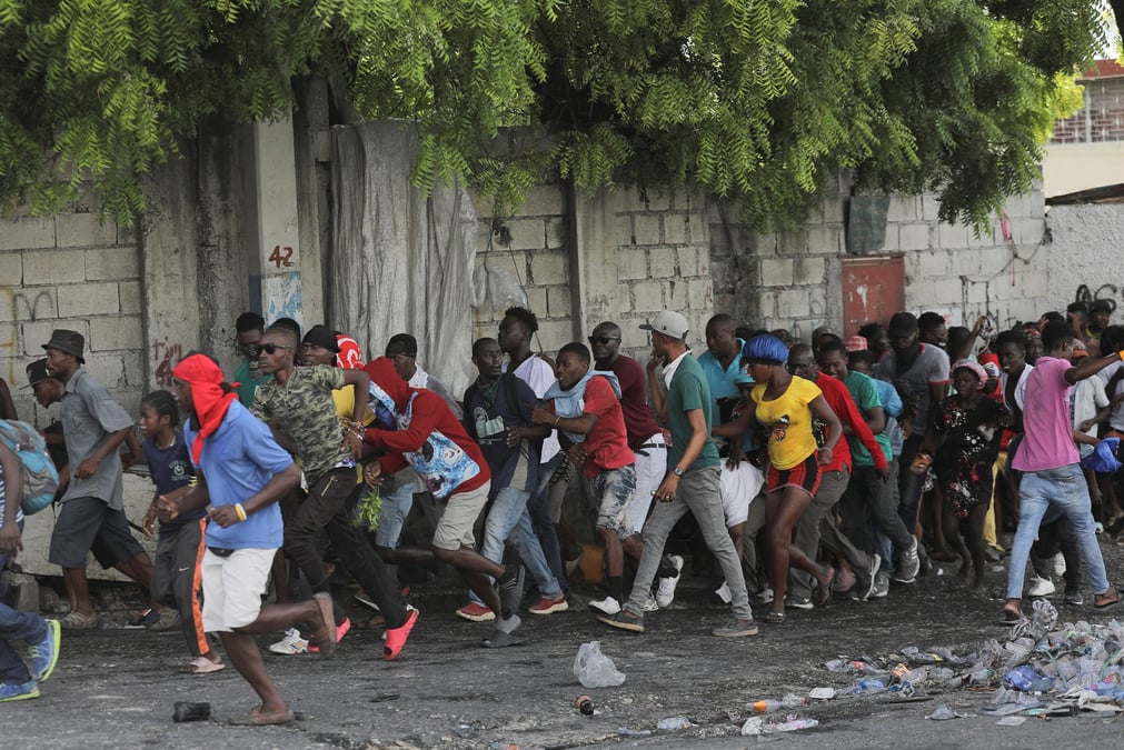 Des personnes s'eloignent apres avoir entendu des coups de feu lors d'une manifestation a port-au-prince