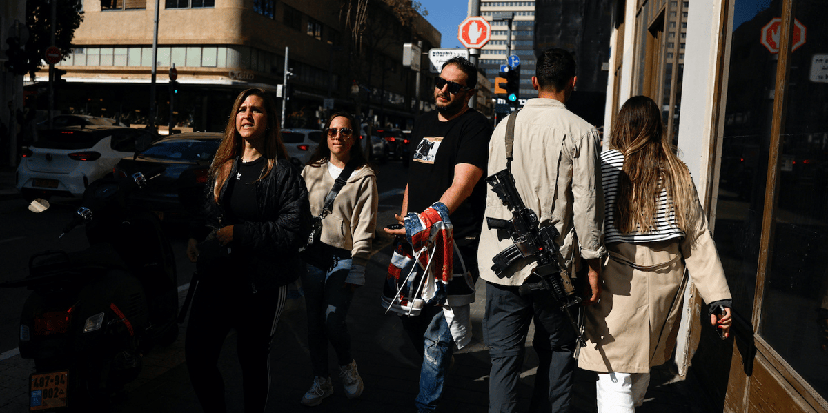 Piétons armés dans la ville de Tel Aviv, vendredi, témoignant du climat de guerre qui règne dans le pays.