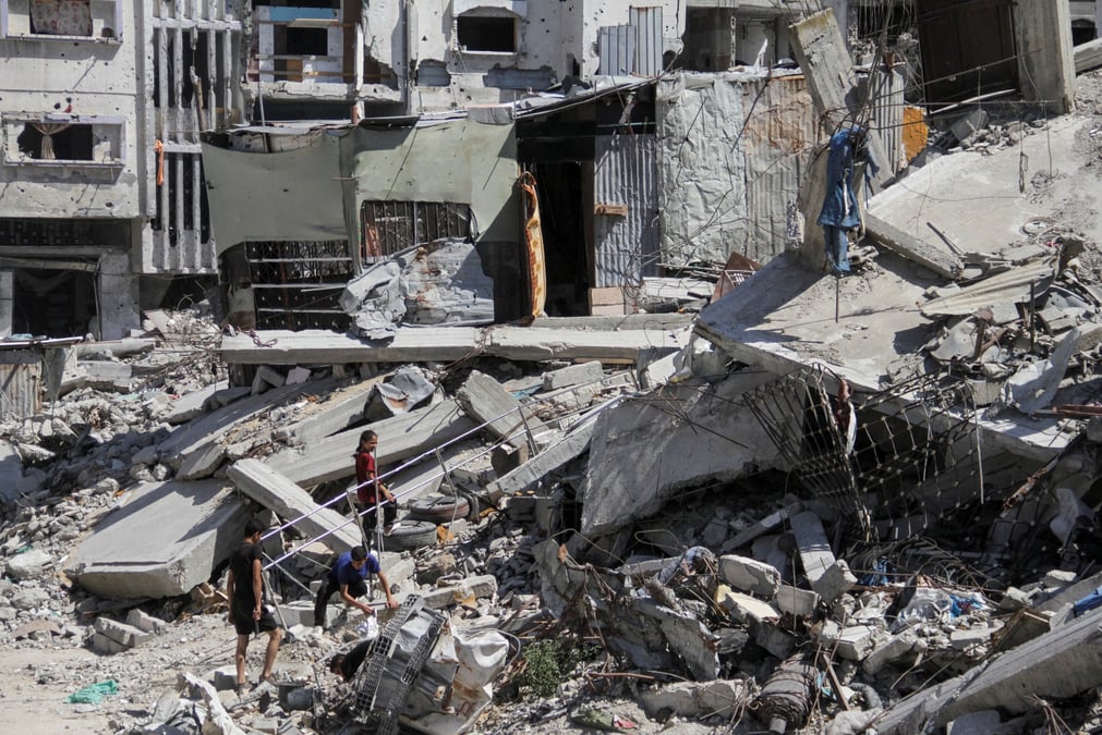 Des palestiniens marchent parmi les decombres de batiments detruits a beit lahia