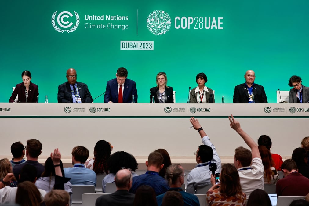 Des personnes levent la main pendant une conference de presse, lors de la conference des nations unies sur le changement climatique (cop28), a dubai