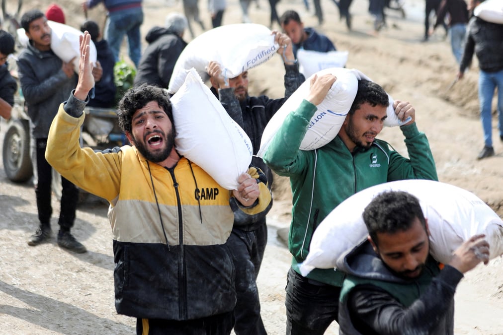 Des palestiniens transportent des sacs de farine recuperes dans un camion humanitaire a gaza