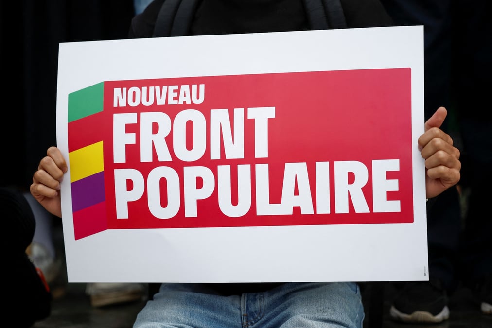 Une personne tient une pancarte avec le logo du nouveau front populaire (nfp)