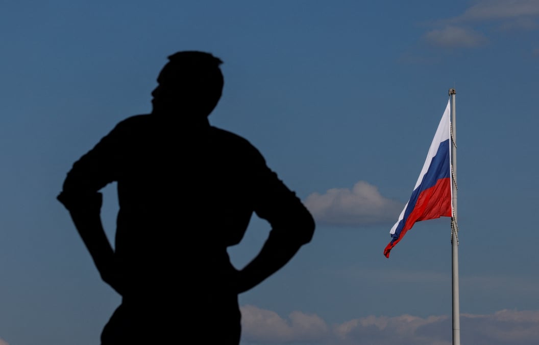 Un homme a cote d'un drapeau national geant de la russie a moscou