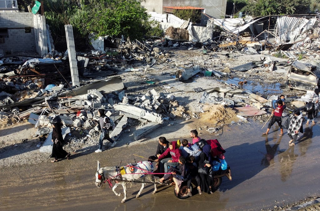 Des palestiniens deplaces rentrent chez eux et passent devant une maison detruite par une attaque israelienne a khan younis, pendant la treve conclue entre le hamas et israel