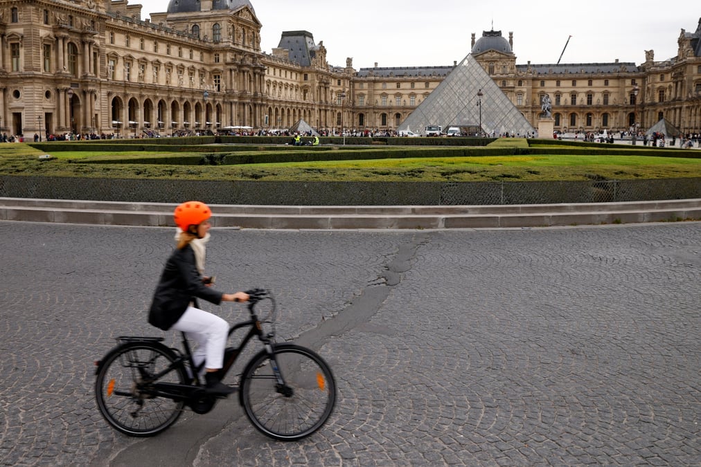 Une femme circule en velo pres de la pyramide du musee du louvre a paris