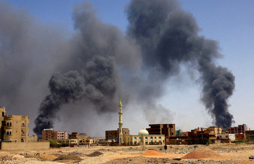 Photo d'archives d'un homme qui marche pendant que la fumee monte au-dessus des batiments apres un bombardement aerien a khartoum nord