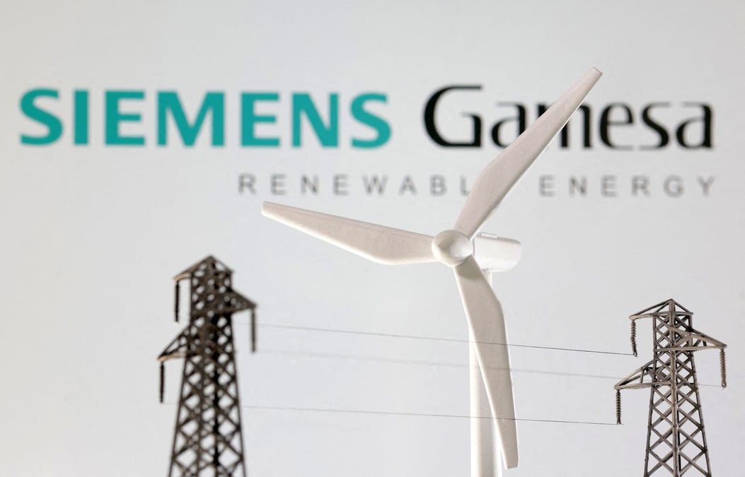 Des miniatures d'eoliennes et de poteaux electriques devant le logo de siemens gamesa