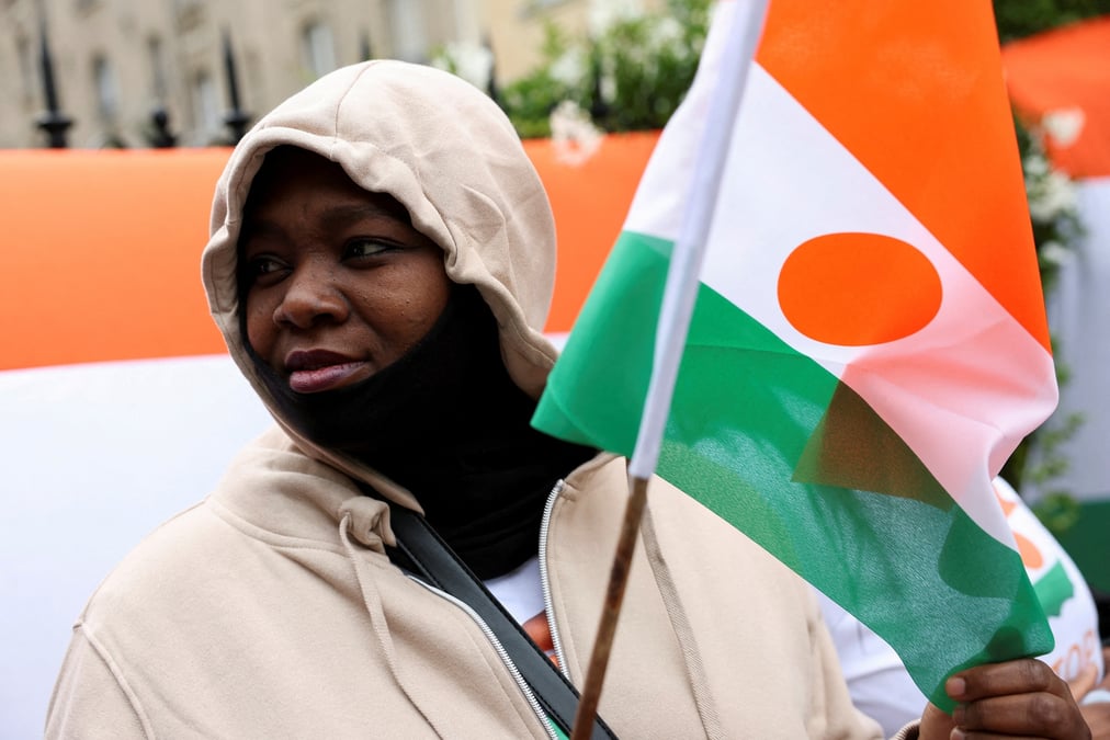 Une personne tient un drapeau du niger devant l'ambassade du niger, a paris