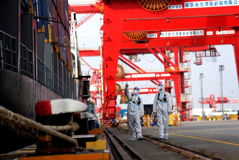 Des agents de la police des frontieres en combinaison de protection patrouillent a cote d'un porte-conteneurs dans le port de nanjing