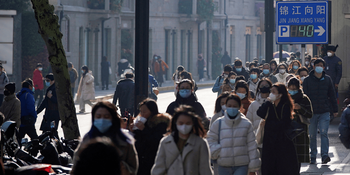 Des personnes portant des masques de protection marchent dans une rue a shanghai, en chine