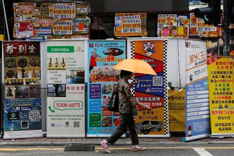 A woman walks past banners promoting retail goods and services displayed in front of closed shops for rent at the shopping mongkok district in hong kong