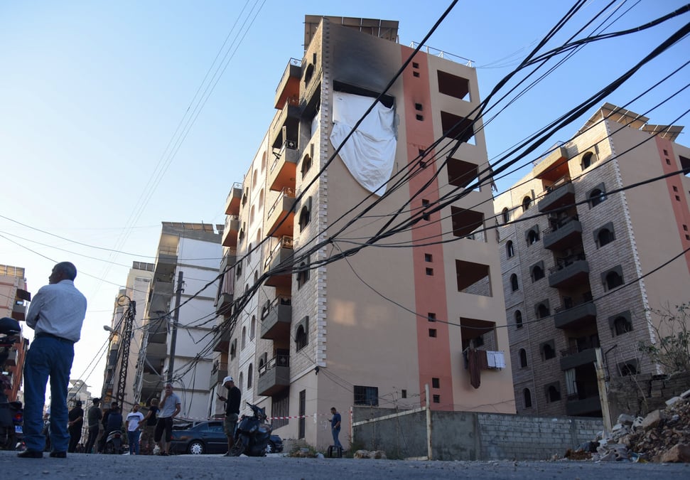 Des personnes se tiennent sur le site touche par une frappe israelienne dans la ville de tripoli, au liban