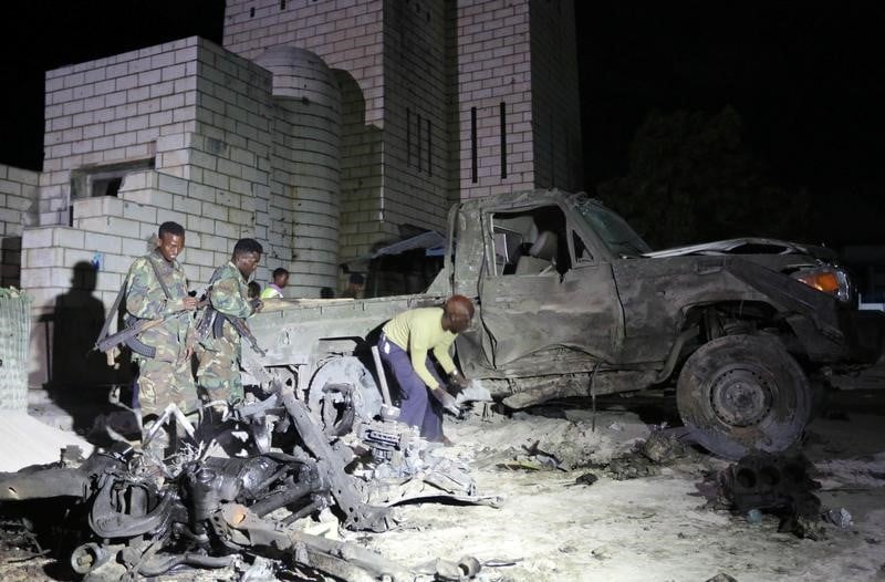 Somali soldiers and policemen inspect the scene of a suicide car explosion near the parliament in the capital mogadishu