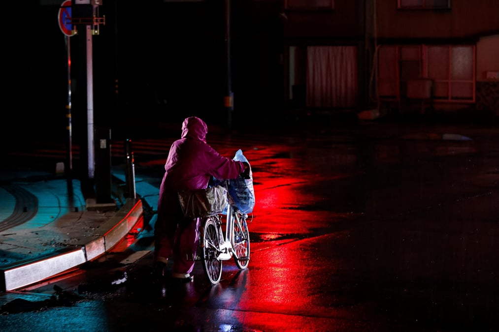 Photo d'une personne qui transporte des affaires et pousse un velo, a la suite d'un tremblement de terre a wajima, au japon