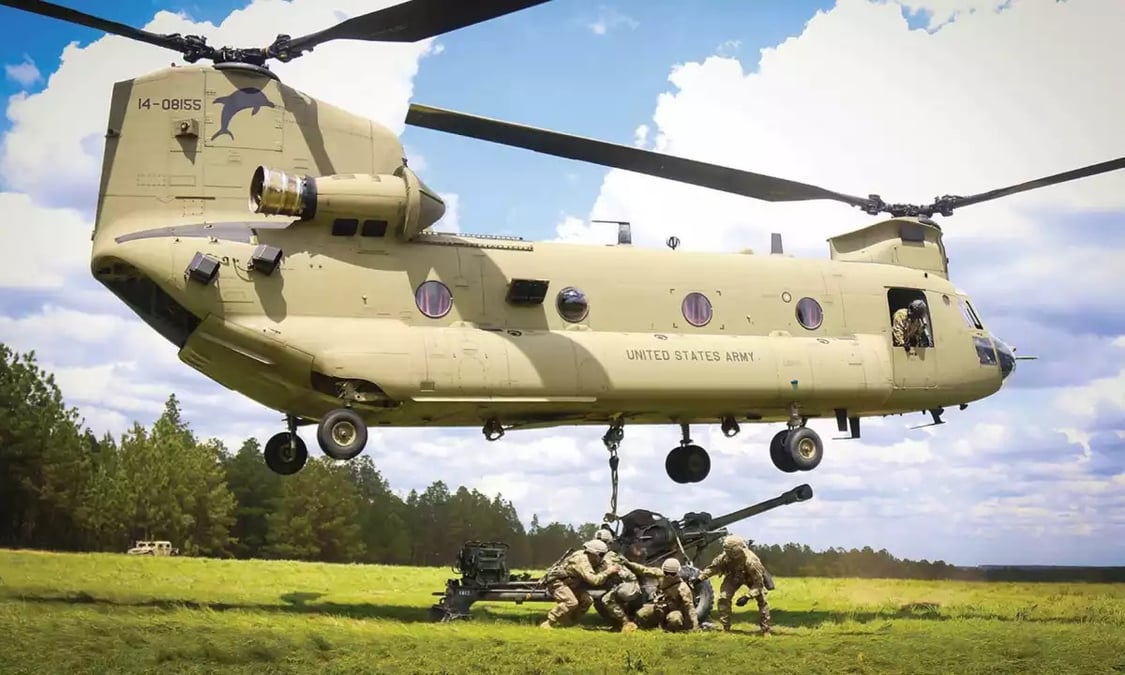 CH-47F Chinook américain en train de transporter une pièce d'artillerie.