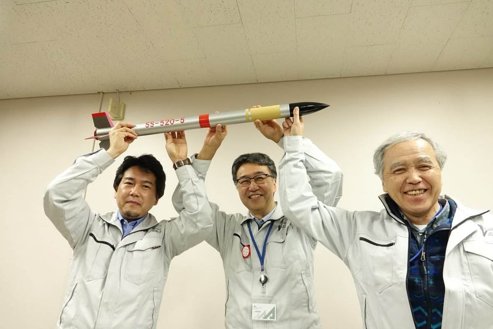 De g. à d. : Hiroto Habu (chef de projet Jaxa), Shinichi Nakasuka (Université de Tokyo) et Yoshifumi Inatani (Isas) brandissent une maquette du SS-520-5 après le vol réussi.