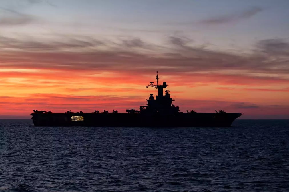 Porte-avions Charles de Gaulle devant un coucher de soleil.