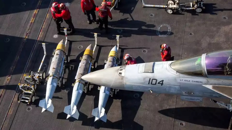 Chargement de bombes JDAM sur un F/A-18F Super Hornet sur le pont d'envol du porte-avions Abraham Lincoln dans le cadre de l'opération Epic Fury (28 février 2026).