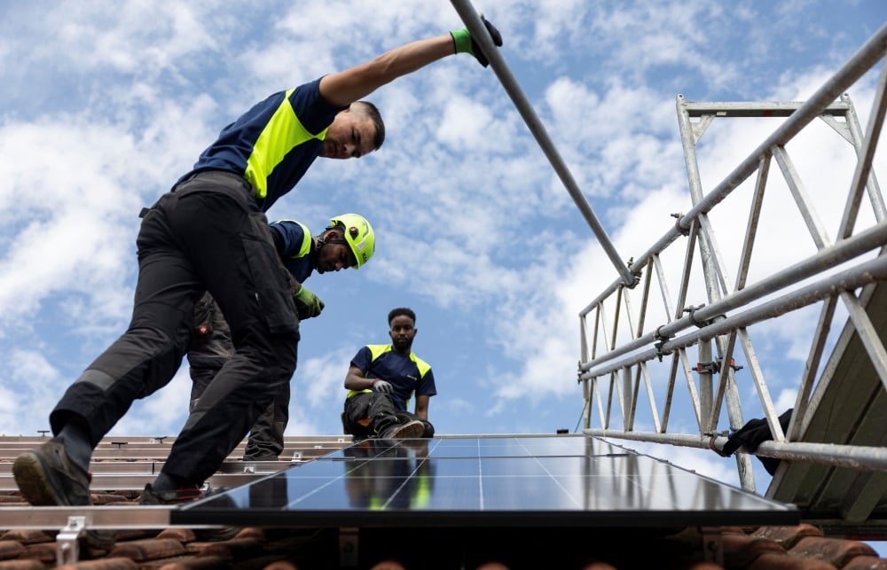 Des salariés de Solarbau24 installent des panneaux solaires sur le toit d’un site en construction, près de Marburg, en Allemagne, 6 août 2025.
