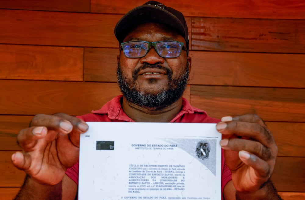 Aurélio Borges, chef d'une communauté quilombola, pose pour des photos avec une copie du titre de propriété du territoire de sa communauté, délivré par l'État du Pará.