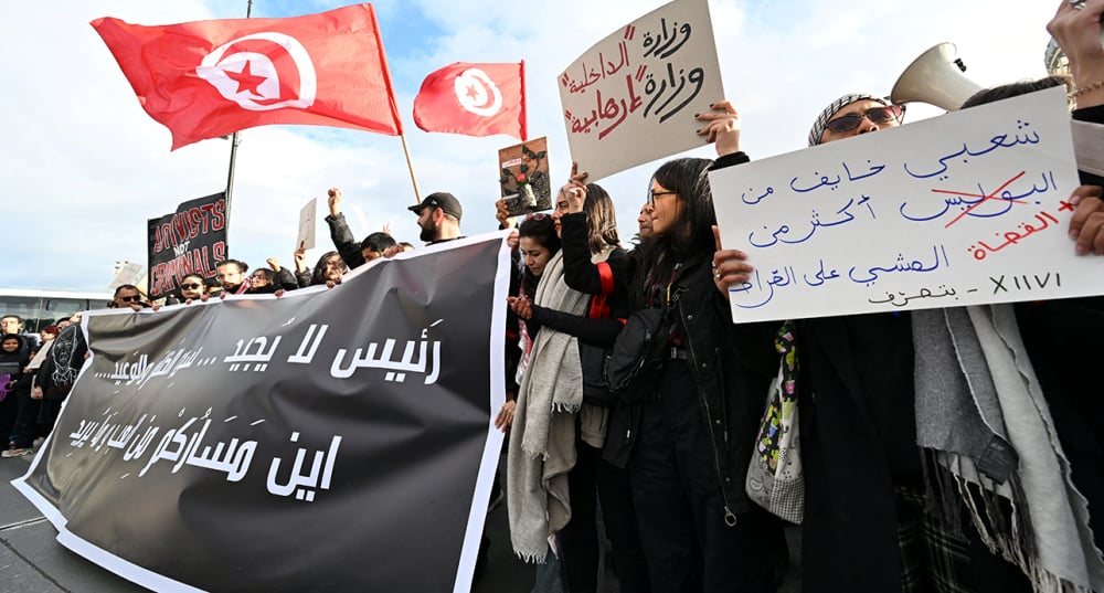 Des Tunisiens brandissent des pancartes lors d'une manifestation baptisée « Marche contre l'injustice », menée par l'opposition et la société civile contre le régime du président tunisien, à Tunis, le 22 novembre 2025