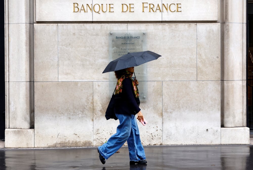 Une femme, parapluie à la main, passe devant le bâtiment de la Banque de France à Paris, le 25 septembre 2024.