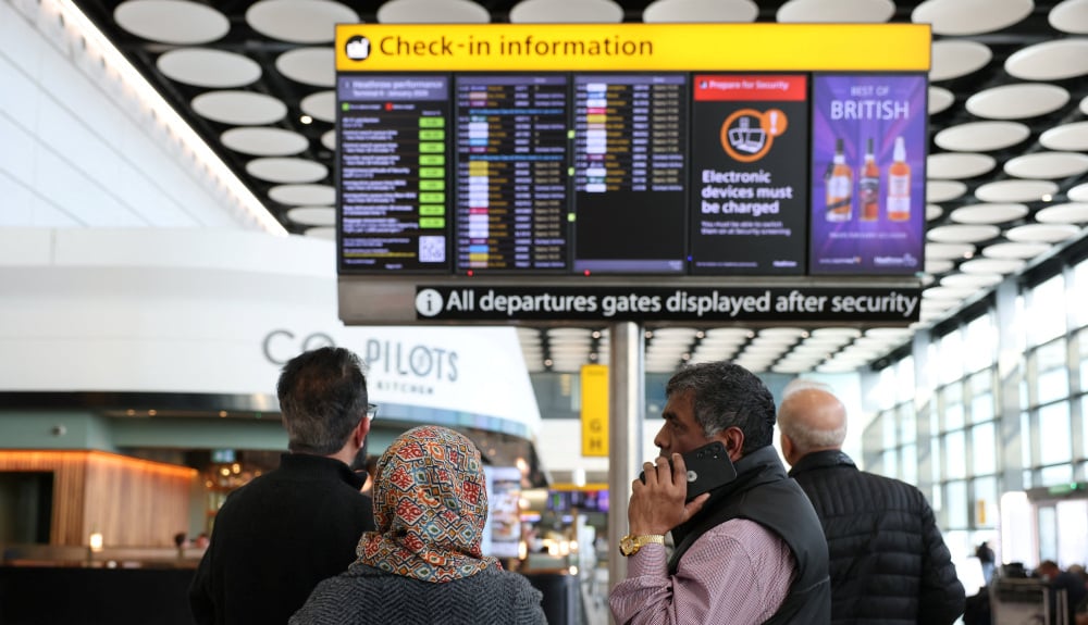 Des voyageurs consultent un tableau d’affichage indiquant les vols annulés vers les pays du Moyen-Orient en raison du conflit entre les États-Unis, Israël et l’Iran, au terminal 4 de l’aéroport d’Heathrow, le 2 mars 2026.