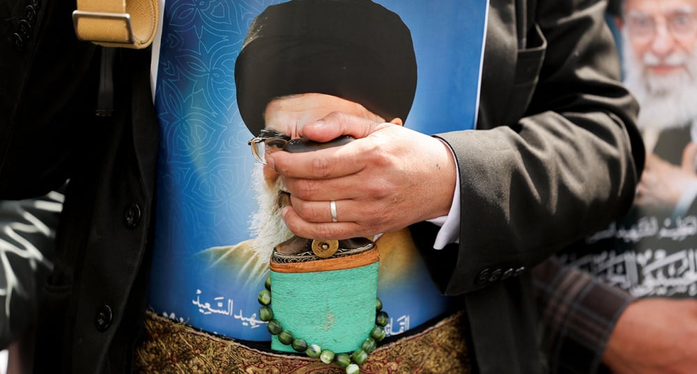 Au Yémen, le 6 mars 2026, un homme portant une affiche à l'effigie d.u défunt guide suprême iranien, l'ayatollah Ali Khamenei