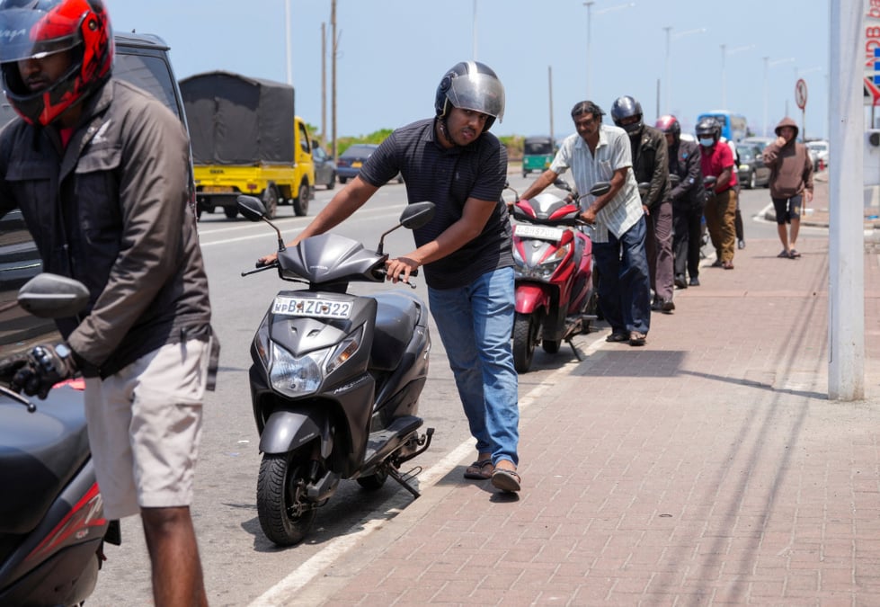 Des personnes font la queue avec leurs scooters devant une station-service à Colombo, au Sri Lanka, le 18 mars 2026, après que le gouvernement a décrété un jour de congé hebdomadaire le mercredi pour les fonctionnaires afin d'économiser le carburant,...