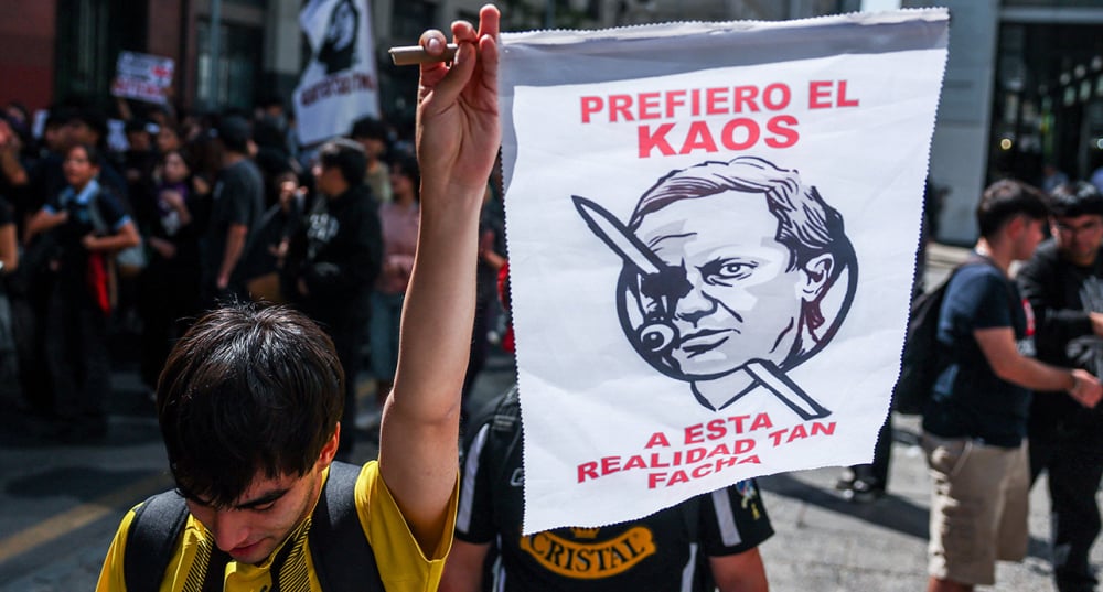 Un manifestant tient une pancarte sur laquelle figure une photo du président chilien José Antonio Kast lors d'une manifestation contre les coupes budgétaires du gouvernement chilien dans le domaine de l'éducation, à Santiago, au Chili, le 26 mars 2026.