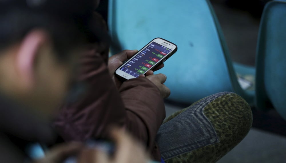 Image d'illustration d'investisseurs qui consultent le cours des actions sur leur téléphone portable.
