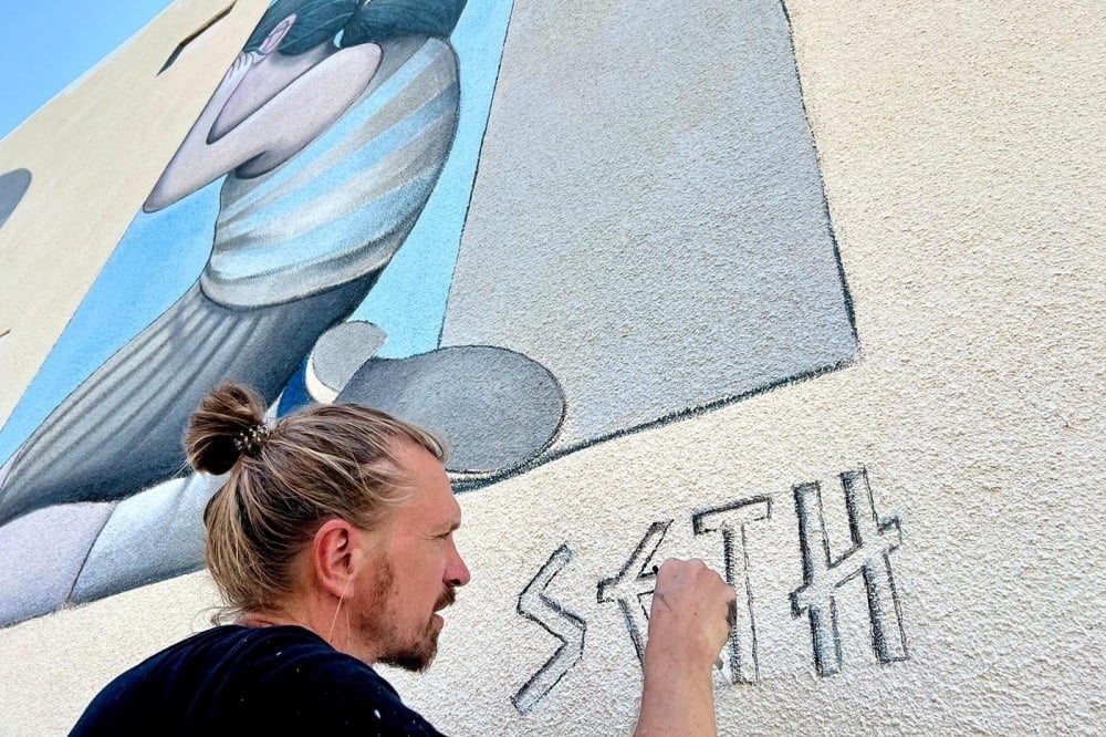 Seth signe une fresque murale de 12 mètres qu'il a peinte à Nicosie (Chypre) en juin 2024.