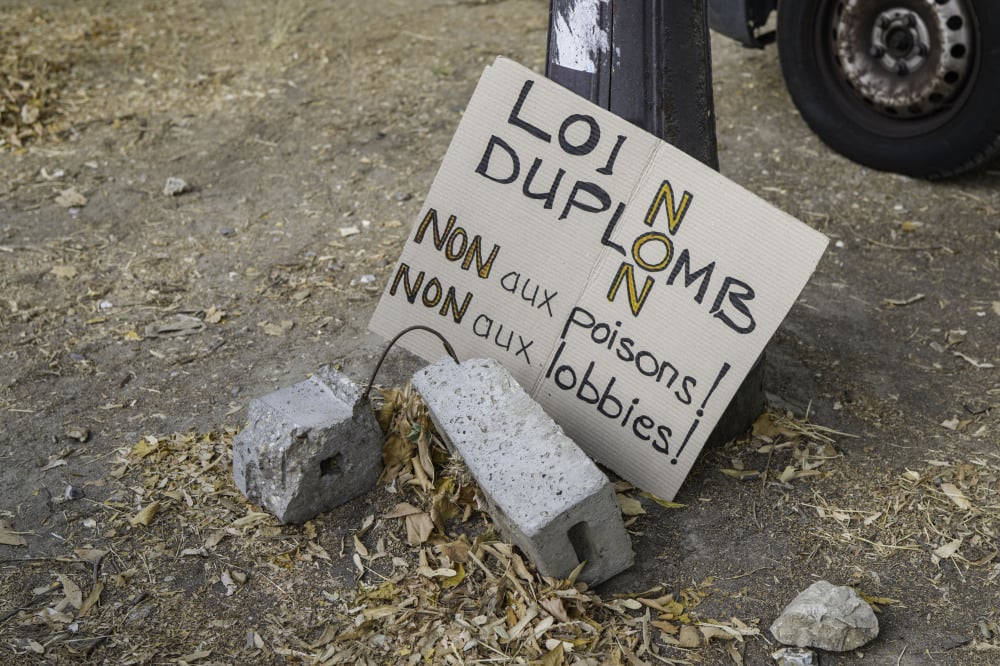 Une pancarte portant l’inscription « Loi Duplomb. Non. Non aux poisons, Non aux lobbies » à Paris, le 20 juillet 2026, non loin de l’Assemblée nationale.
