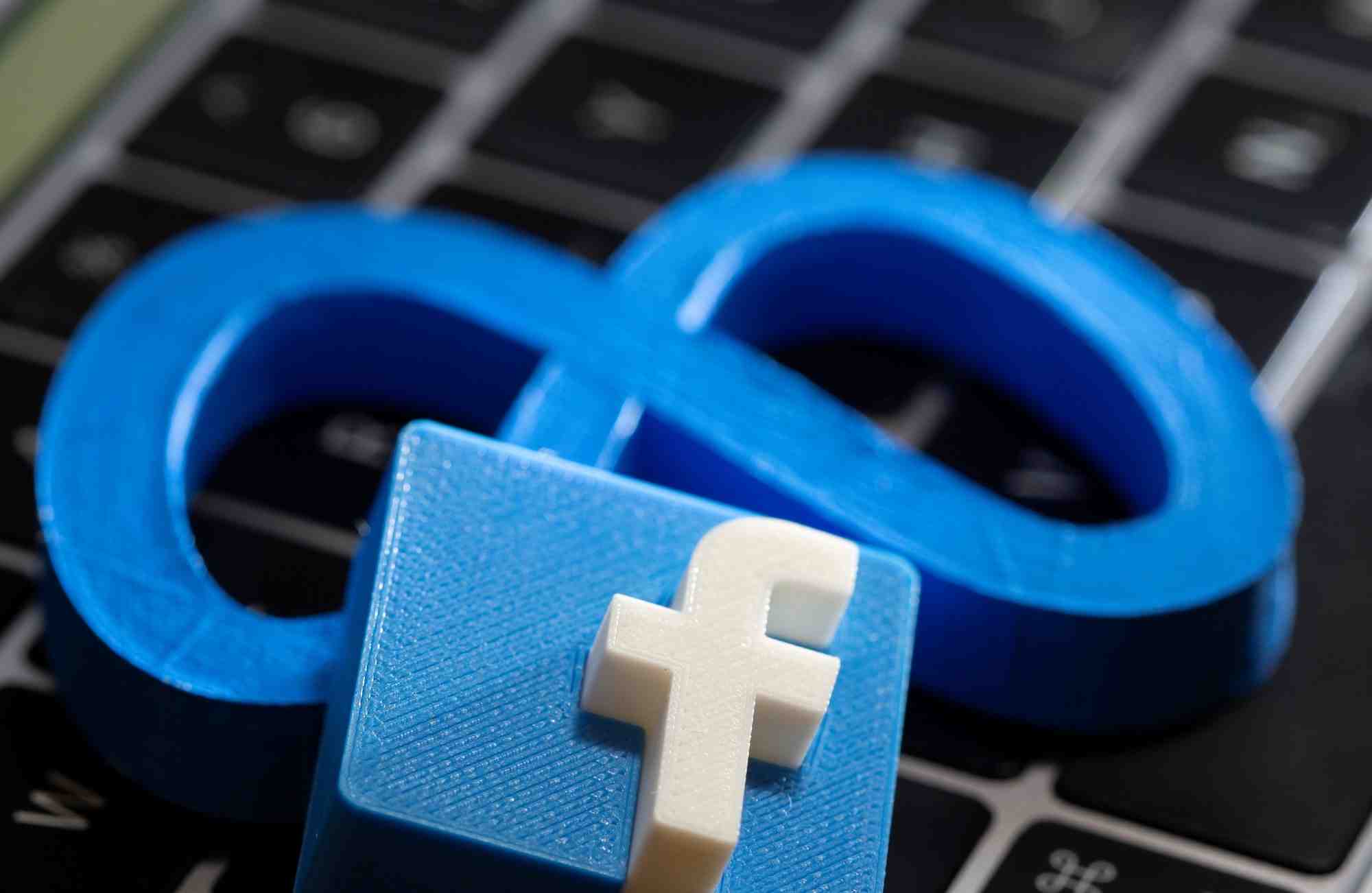 Une impression 3d du nouveau logo de facebook meta et le logo de facebook sont places sur le clavier d'un ordinateur portable dans cette illustration