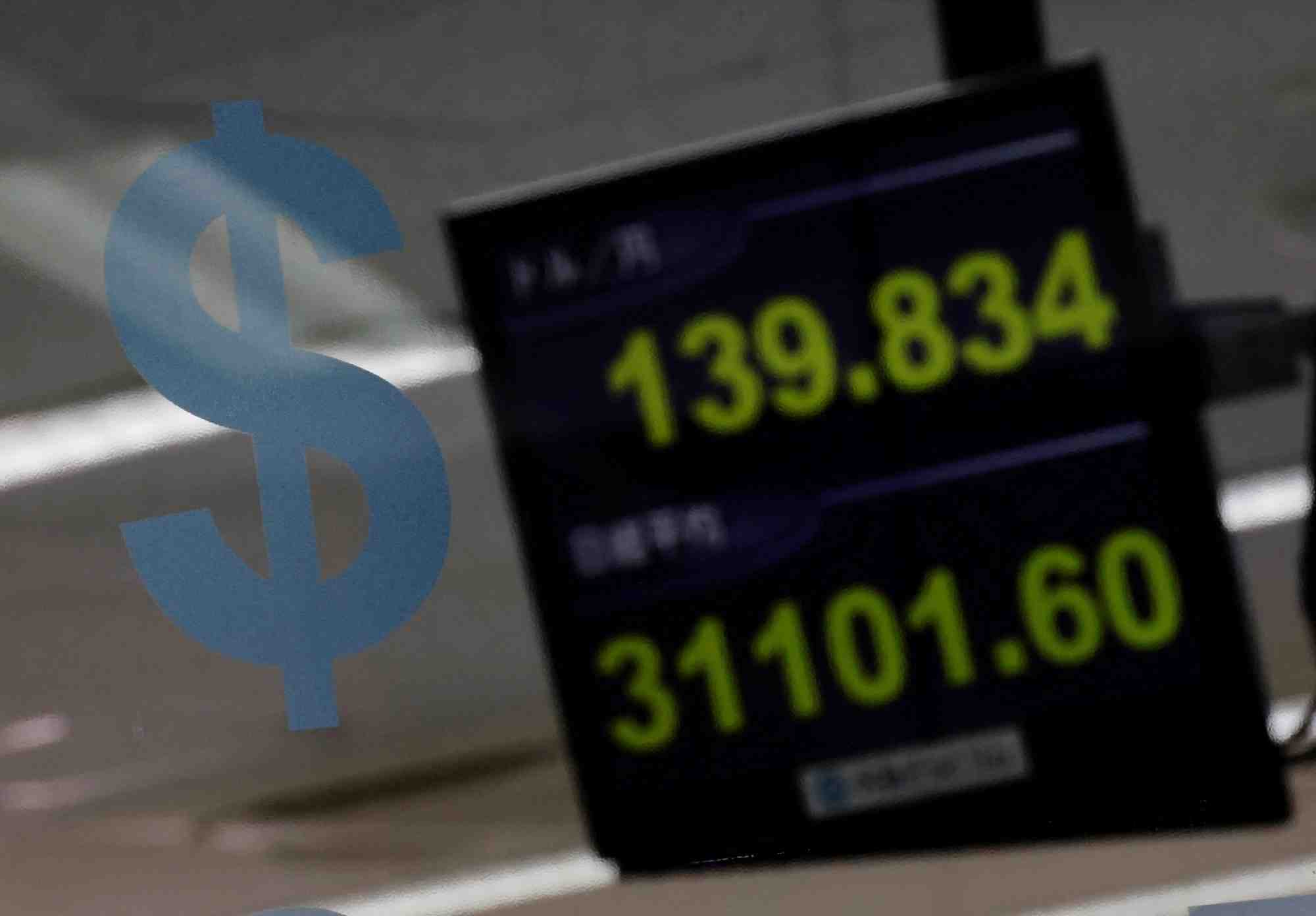 Un logo du dollar americain et la valeur du yen a la societe d'echange de devises gaitame.com a tokyo