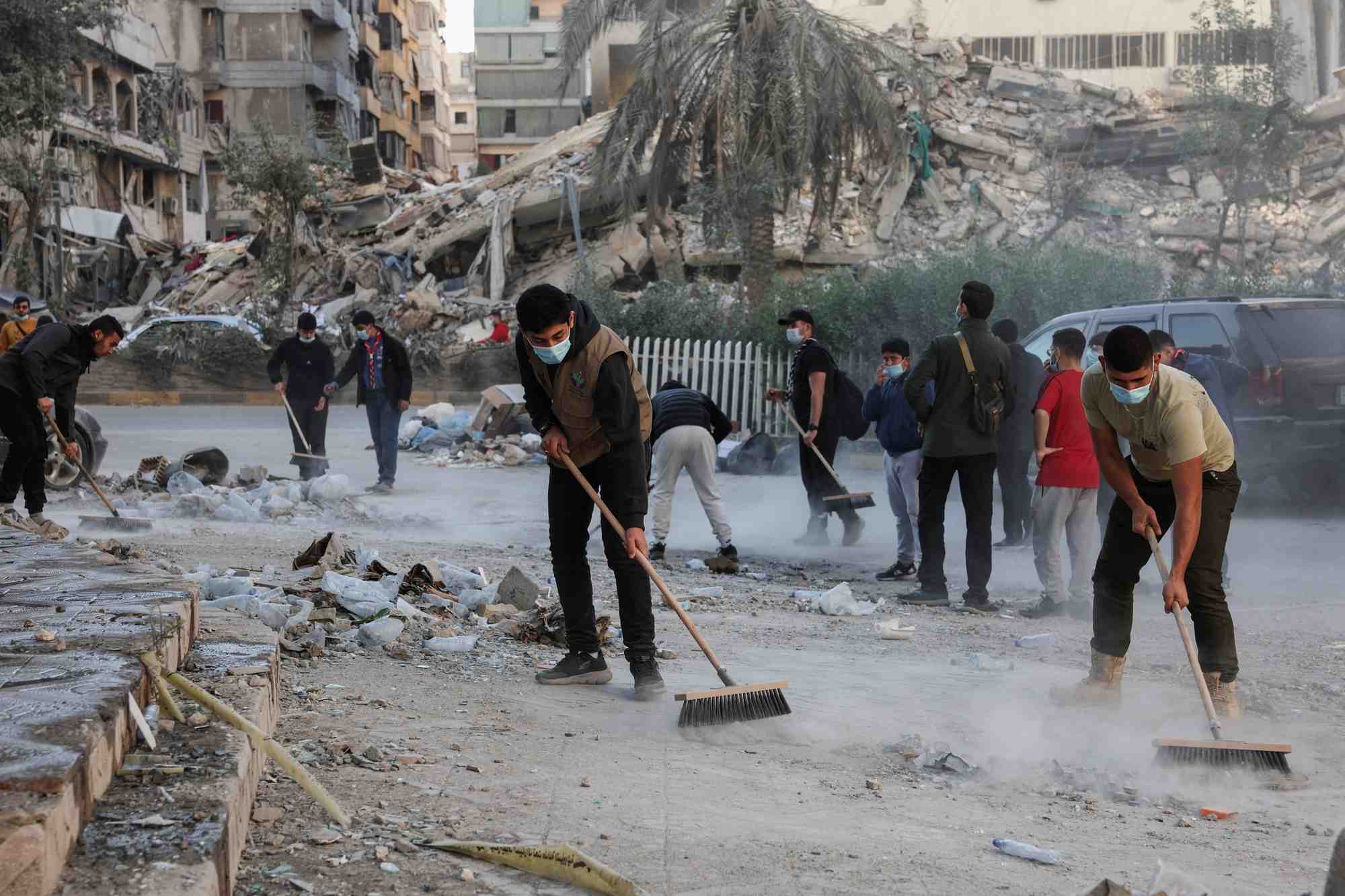 Des membres des scouts de l'imam al-mahdi nettoient les decombres et les debris des batiments endommages dans les banlieues sud de beyrouth