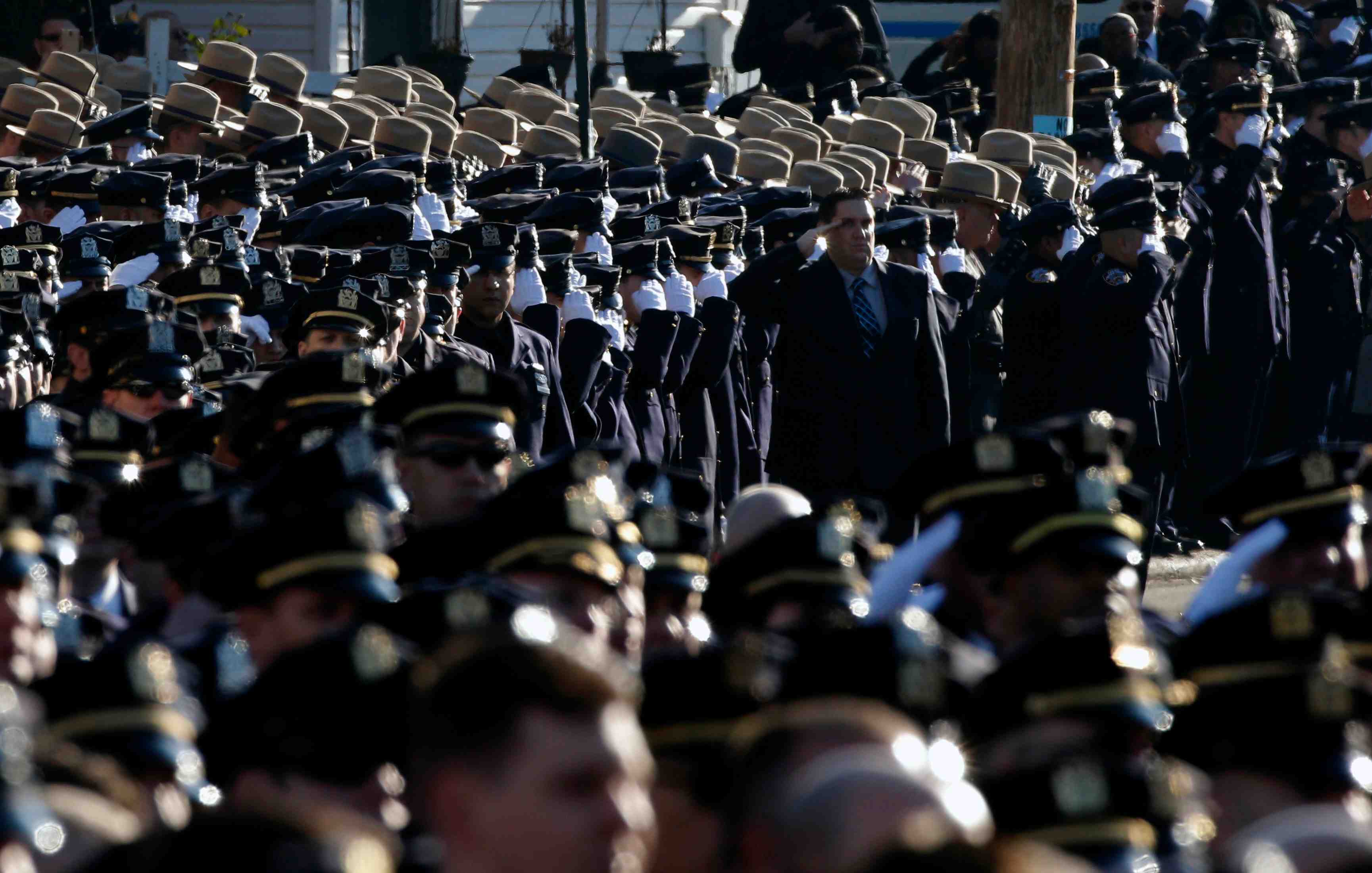 Police salute during the playing of the u.s. national anthem outside the christ tabernacle church at the start of the funeral service for slain nypd officer ramos in the queens borough of new york