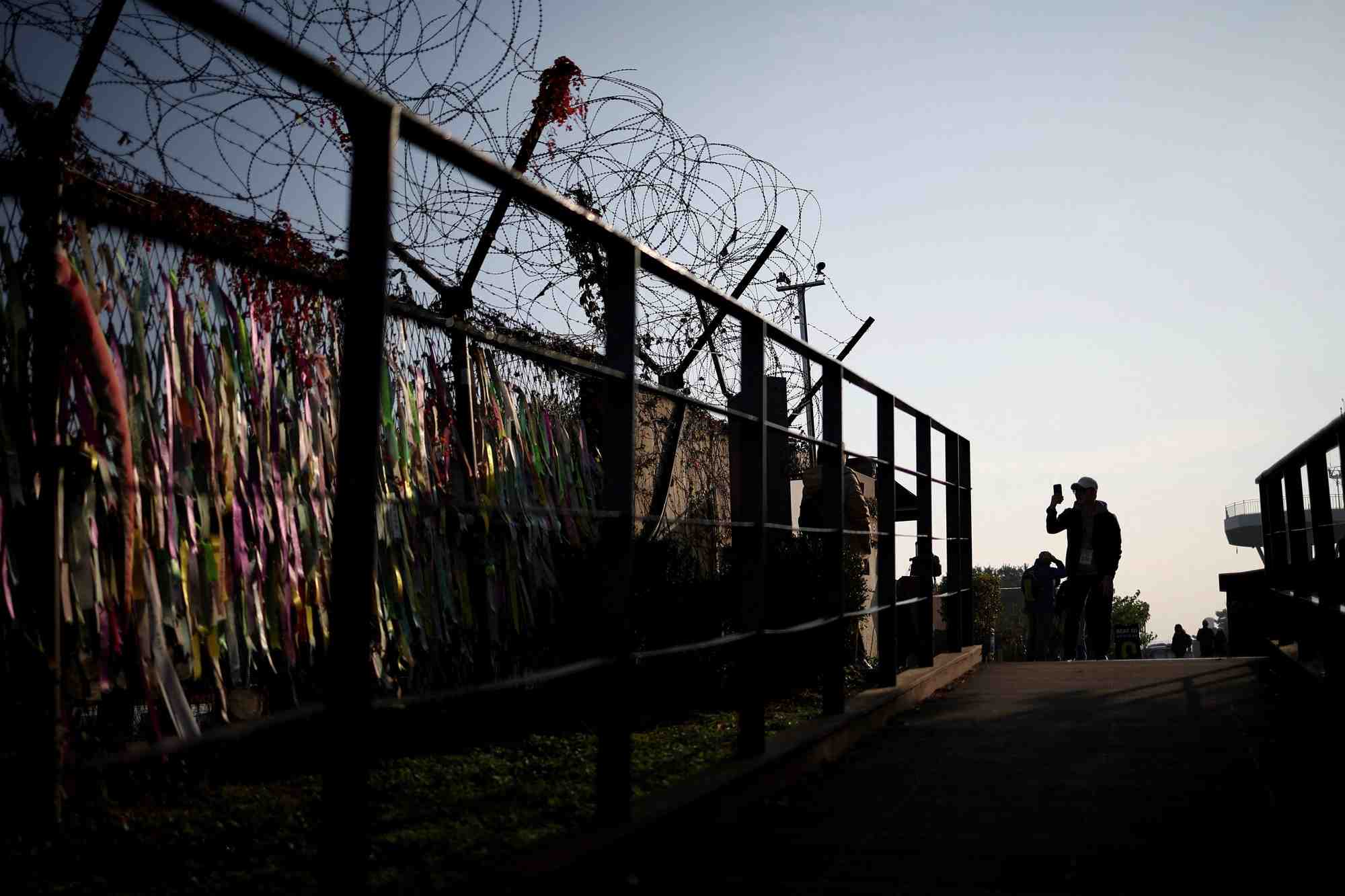 Un homme prend des photographies devant une cloture militaire pres de la zone demilitarisee separant les deux corees