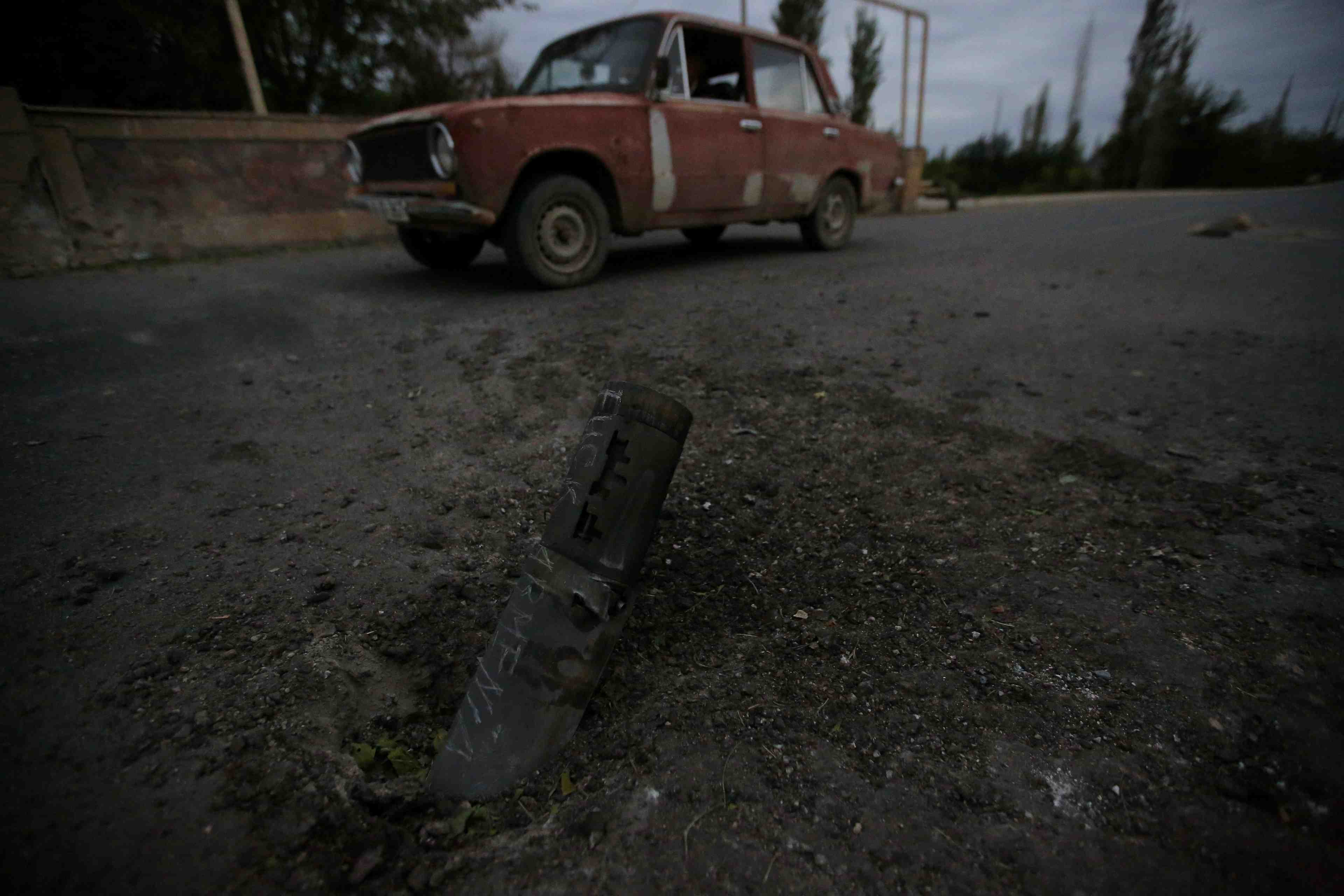 A car drives past the remains of spent ammunition following a recent shelling in tartar