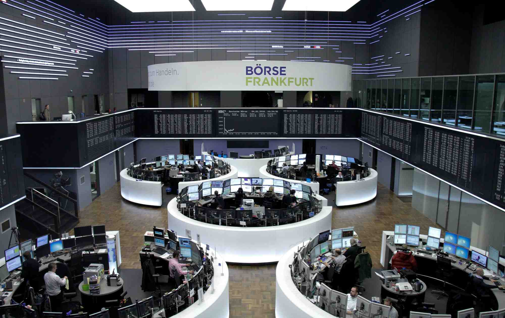Des traders sont photographies a leur bureau devant le tableau du dax a la bourse de francfort