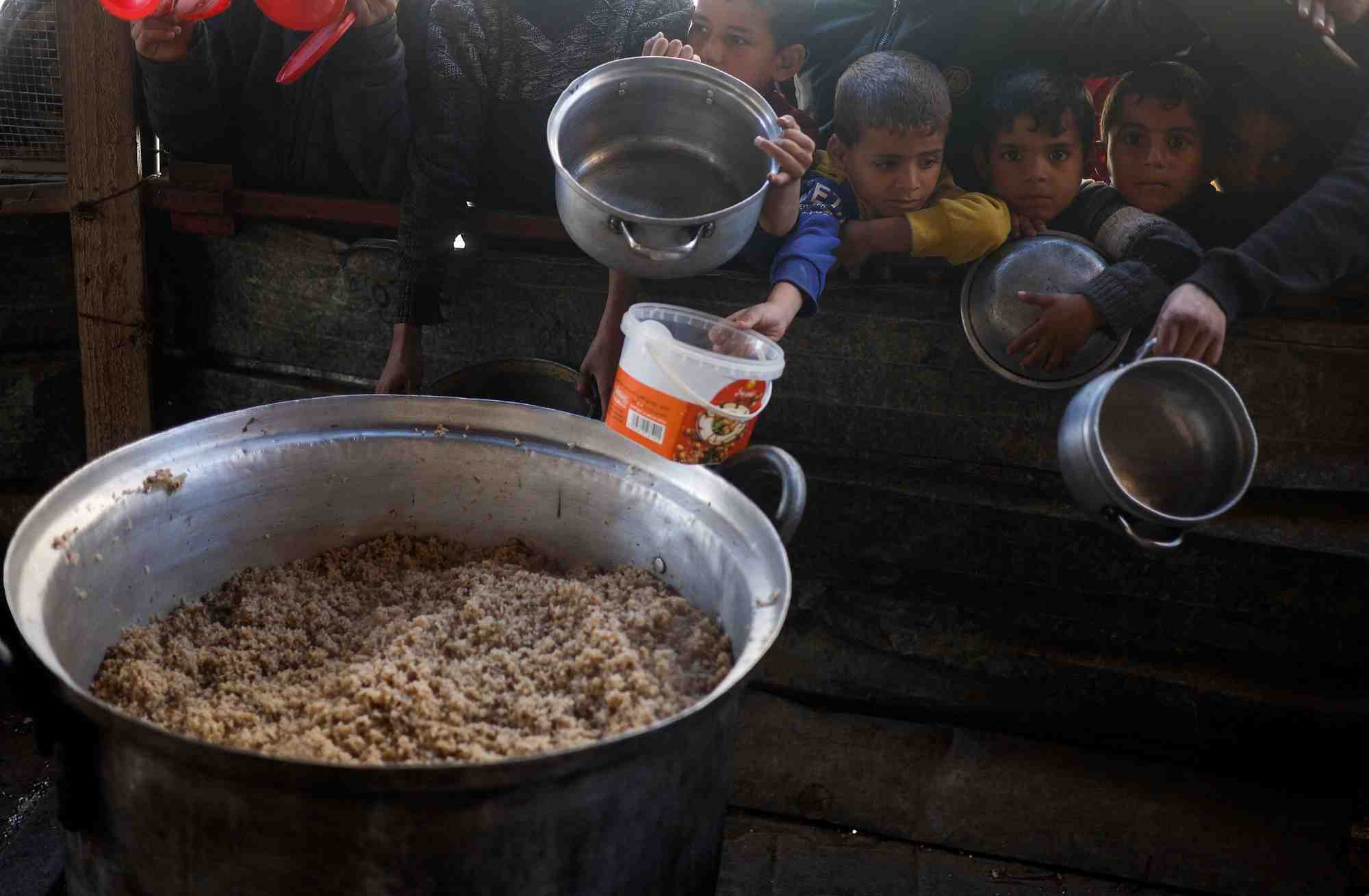 Des enfants palestiniens attendent de recevoir de la nourriture preparee par une cuisine caritative dans un contexte de penurie alimentaire, a rafah