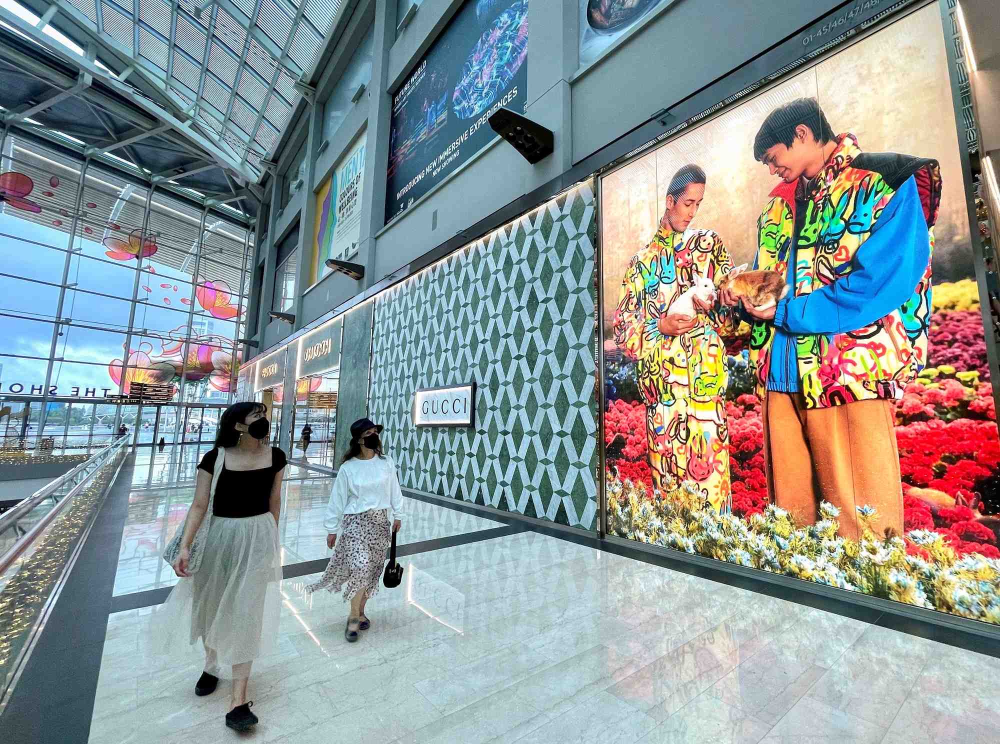 Des visiteurs passent devant une boutique gucci au marina bay sands a singapour