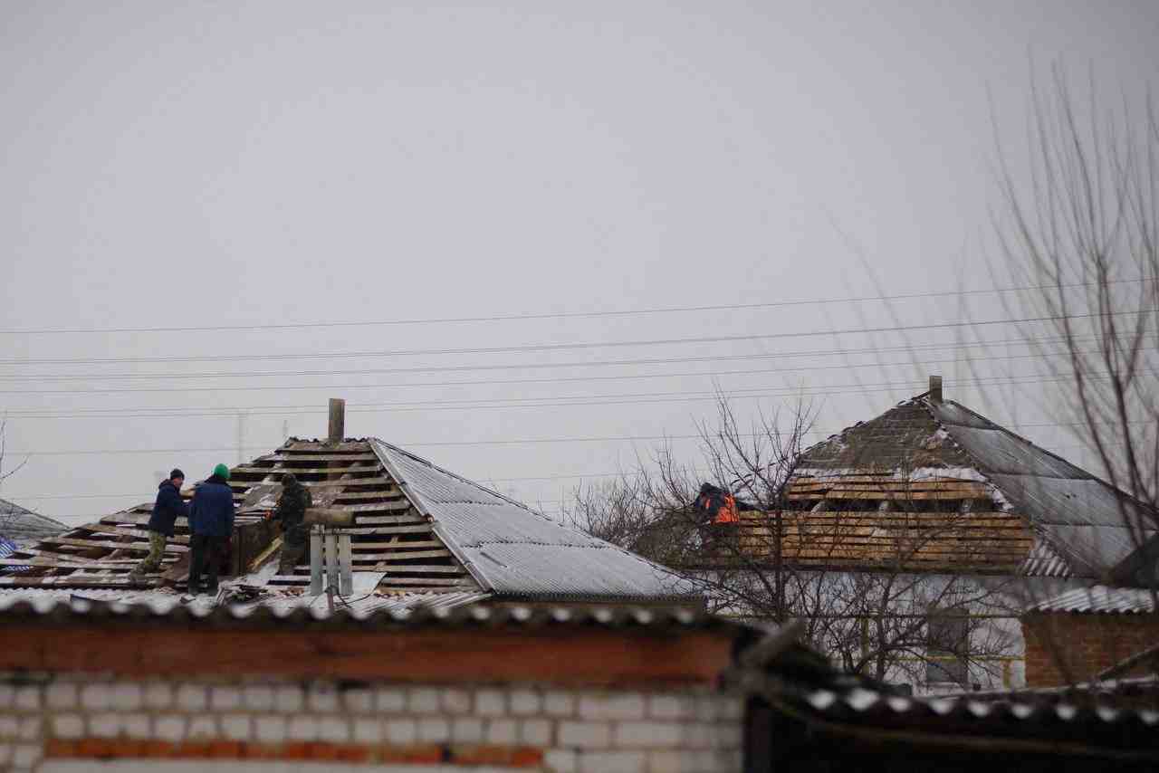 Photo des ouvriers qui reparent le toit d'une maison endommagee du village de petropavlovka, accidentellement bombarde par un avion militaire russe dans l'ouest de la russie